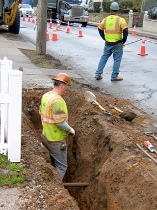 Workers hand digging trench